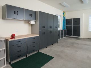 Modern custom garage organization setup with dark cabinets and wooden workbench in Chandler, AZ
