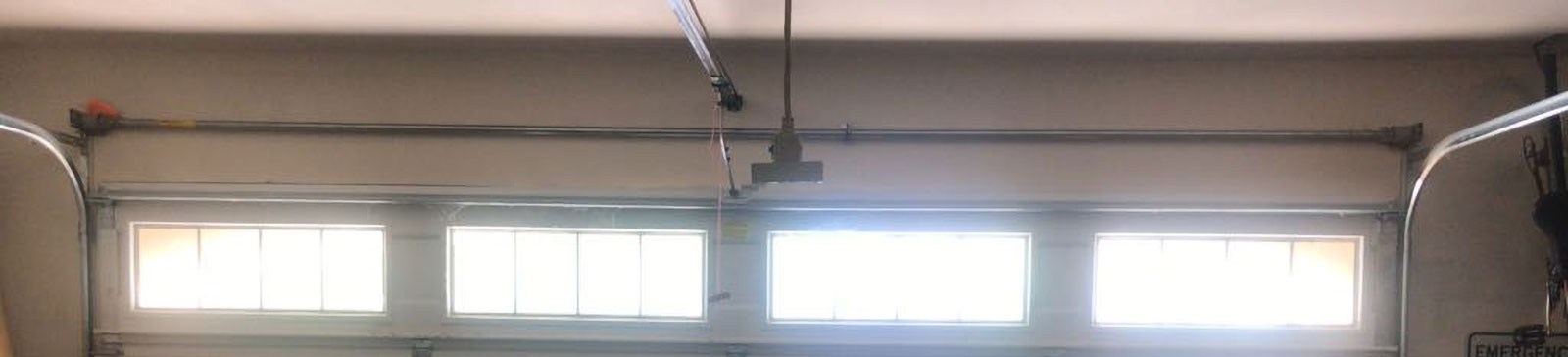 Wide view of white residential sectional garage door in Phoenix, AZ after professional cables and tracks replacement.